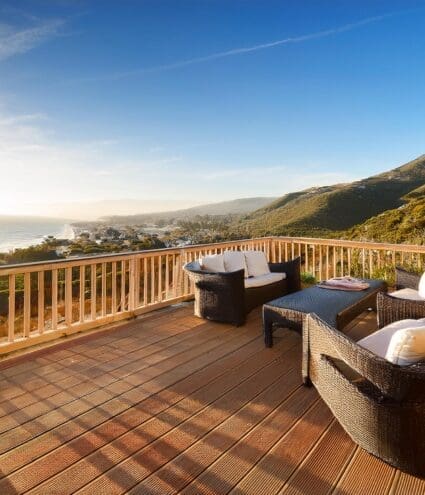 A spacious wooden deck furnished with outdoor seating, overlooking a coastal California landscape. J Kidd Construction